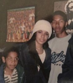 a man and two women posing for a photo in front of a wall with pictures on it