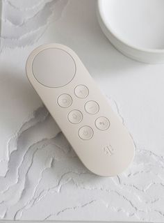 a remote control sitting on top of a table next to a white cup and saucer