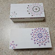 two white boxes with designs on them sitting on a counter top next to each other