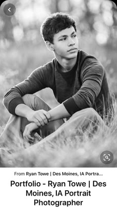 a black and white photo of a boy sitting in the grass with his hands on his knees