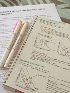 two pencils sitting on top of a notebook next to some papers with diagrams and graphs