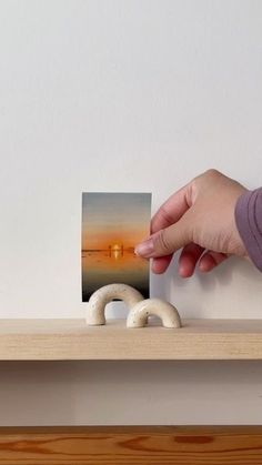 a person is holding up a photograph on a shelf with two white rings in front of them