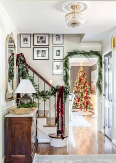 a christmas tree sitting on top of a banister next to a stair case filled with wreaths