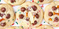 chocolate chip cookies with sprinkles and candy on top are arranged in rows