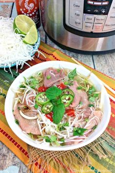 a white bowl filled with meat and vegetables next to an instant pot