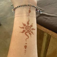 a woman's arm with a tattoo on it that has an image of a sun