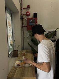 a man standing in front of a counter with food on it and looking at his cell phone