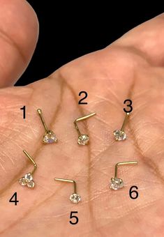 four different types of nose piercings on someone's hand with the measurements for them