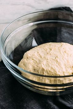 a glass bowl filled with dough on top of a black cloth