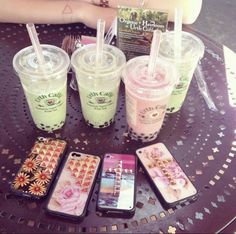 four cell phones sitting on top of a table next to two cups with straws