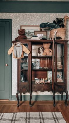 an old wooden cabinet with stuffed animals on top and bookshelf in the corner