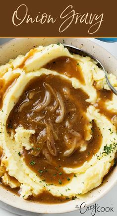 a bowl filled with mashed potatoes and gravy on top of a table