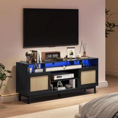 an entertainment center with blue lights on the bottom shelf and two speakers in front of a flat screen tv