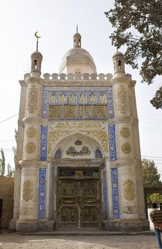 an ornate building with blue and white tiles on it's front door, surrounded by trees