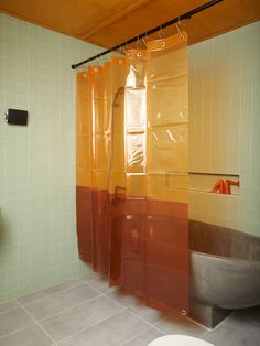 a bathroom with yellow and orange shower curtain next to a bathtub in the corner