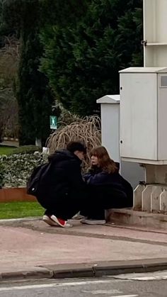 two people sitting on the ground near a building