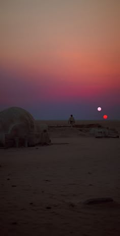 the sun is setting in the distance over some sand structures