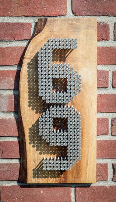 a sign made out of beer bottle caps on a wooden board next to a brick wall