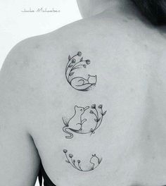 the back of a woman's shoulder with three cats and flowers on her left side