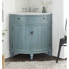 a bathroom with a blue vanity and white walls, rugs and flowers on the floor