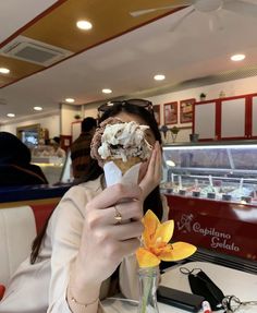 a woman eating an ice cream sundae at a restaurant with flowers in front of her