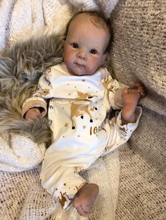 a baby laying on top of a white blanket