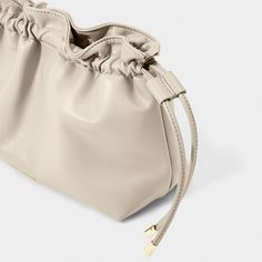 Discover the latest addition to the Katie Loxton family - the Hailey Crossbody Clutch in greige! This versatile bag offers you two stylish ways to wear it - either as a trendy crossbody for an effortless day look or as an elegant clutch to elevate any evening outfit. With its drawstring closure detail, vegan leather material, and gleaming gold-tone hardware, this bag exudes understated luxury and attention to detail. Sure to become a staple in your wardrobe, and a piece you can rely on for years Versatile Taupe Shoulder Bag For Travel, Versatile Beige Pouch Bag, Chic Taupe Bag For Everyday Use, Neutral Crossbody Shoulder Bag With Removable Pouch, Versatile Taupe Crossbody Bag, Versatile Neutral Bag With Adjustable Strap, Versatile Cream Pouch Bag, Chic Taupe Shoulder Bag For Everyday, Versatile Taupe Shoulder Bag