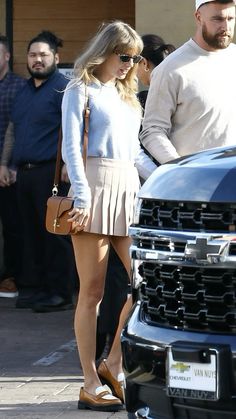 a man and woman are walking down the street in front of a truck with people looking on