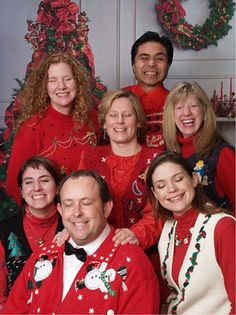 a group of people in red christmas sweaters posing for a photo next to a christmas tree