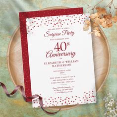 a red and white wedding anniversary party card on a plate with flowers in the background