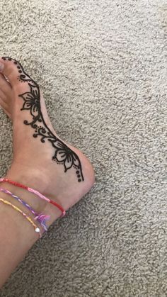 a woman's foot with henna tattoos on her left leg and ankle bracelets