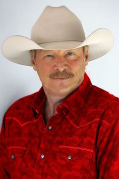 a man wearing a cowboy hat poses for a photo in front of a white background