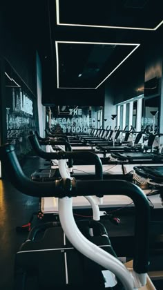 rows of exercise bikes in a gym with mirrors and lights on the wall behind them