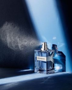 a bottle of perfume sitting on top of a blue table next to a black wall