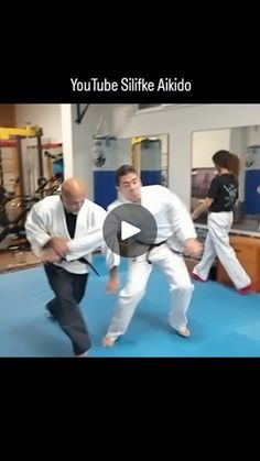 two men are practicing martial moves in a room with blue carpet and mirrors on the walls