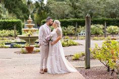 a bride and groom standing in front of a fountain