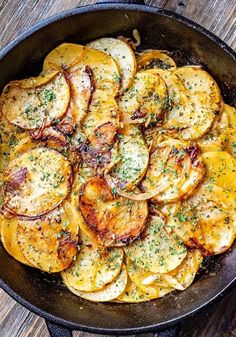 a skillet filled with sliced potatoes on top of a wooden table