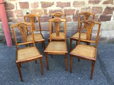 six wooden chairs sitting next to each other in front of a brick wall