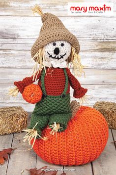 a knitted scarecrow sitting on top of a pumpkin