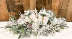 the centerpiece is decorated with pine cones, evergreens and white frosted candles