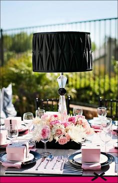 the table is set with pink and white flowers, candles, and black napkins