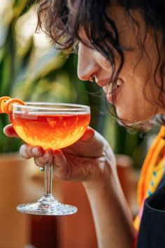 a woman holding a wine glass filled with liquid