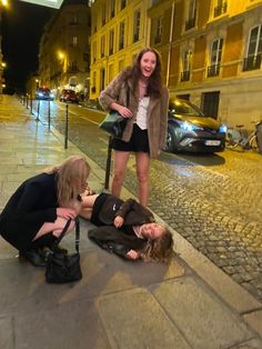 two women are on the street with luggage and one is trying to help another woman