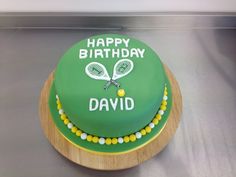 a green birthday cake with tennis racquets on it's side and the words happy birthday david