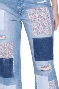 a woman wearing blue jeans with patches on the side and pockets that have been cut off