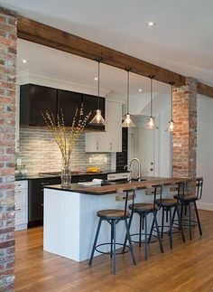 an open concept kitchen and dining room with exposed brick wall, hardwood flooring and bar stools