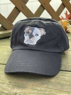 a black hat with a koala embroidered on it sitting on a wooden table next to leaves