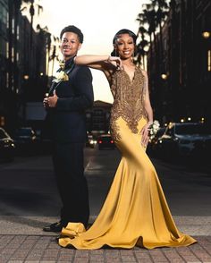 a man and woman in formal wear posing for the camera on a city street at night