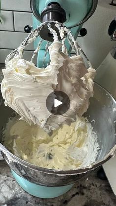 a mixing bowl filled with white frosting on top of a counter