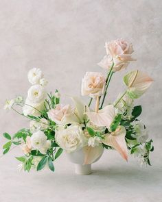 a vase filled with white flowers and greenery